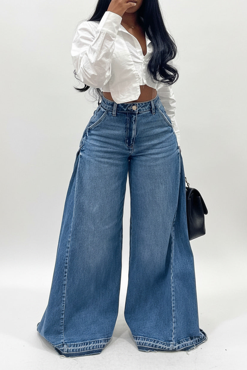 Person wearing high-waisted blue jeans and a white blouse against a plain background