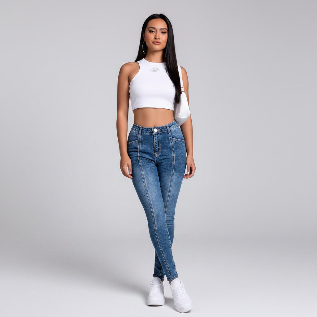 Woman in white crop top and blue jeans posing in an indoor setting