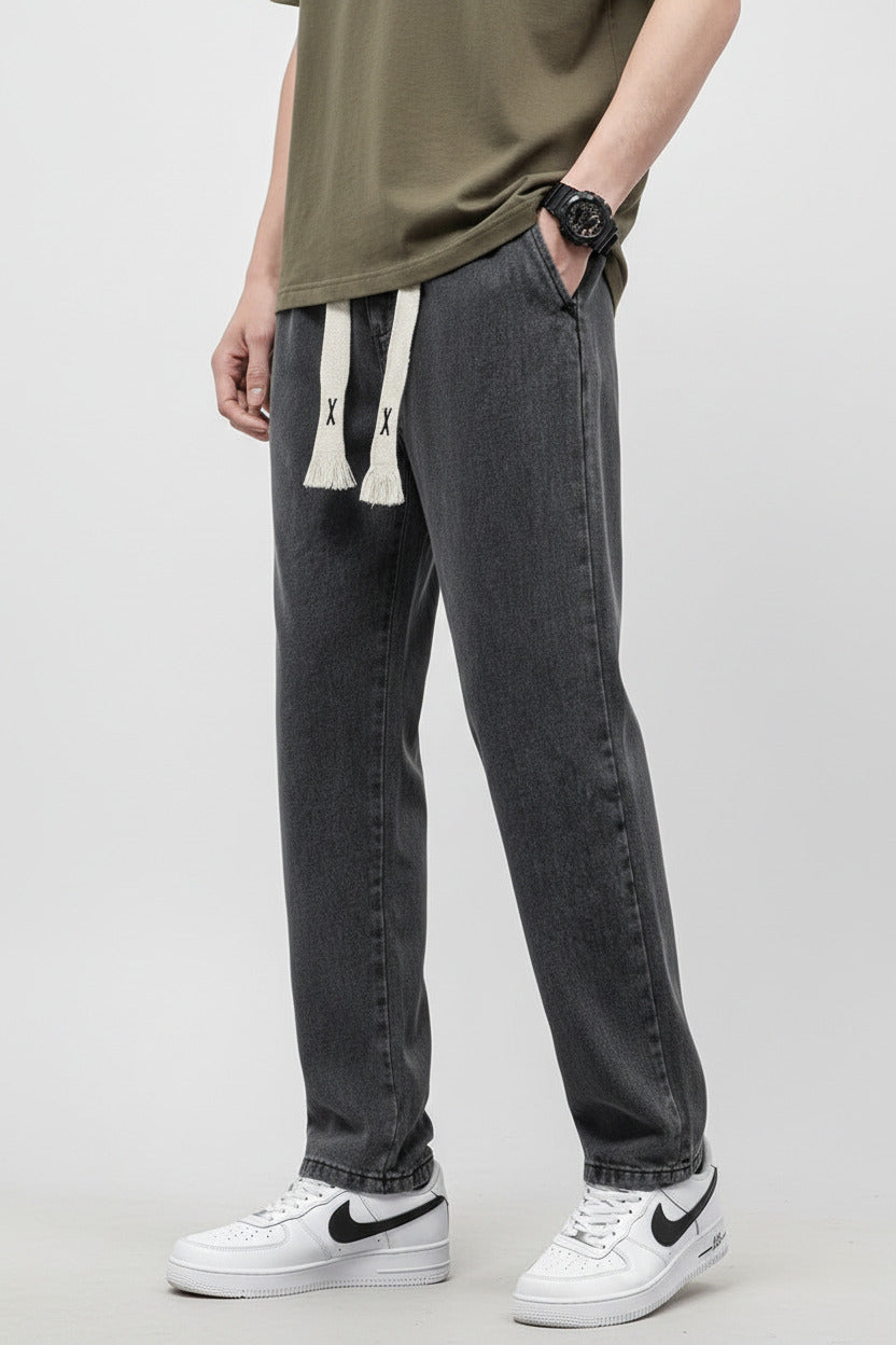 Person wearing gray jeans and a brown shirt against a white background