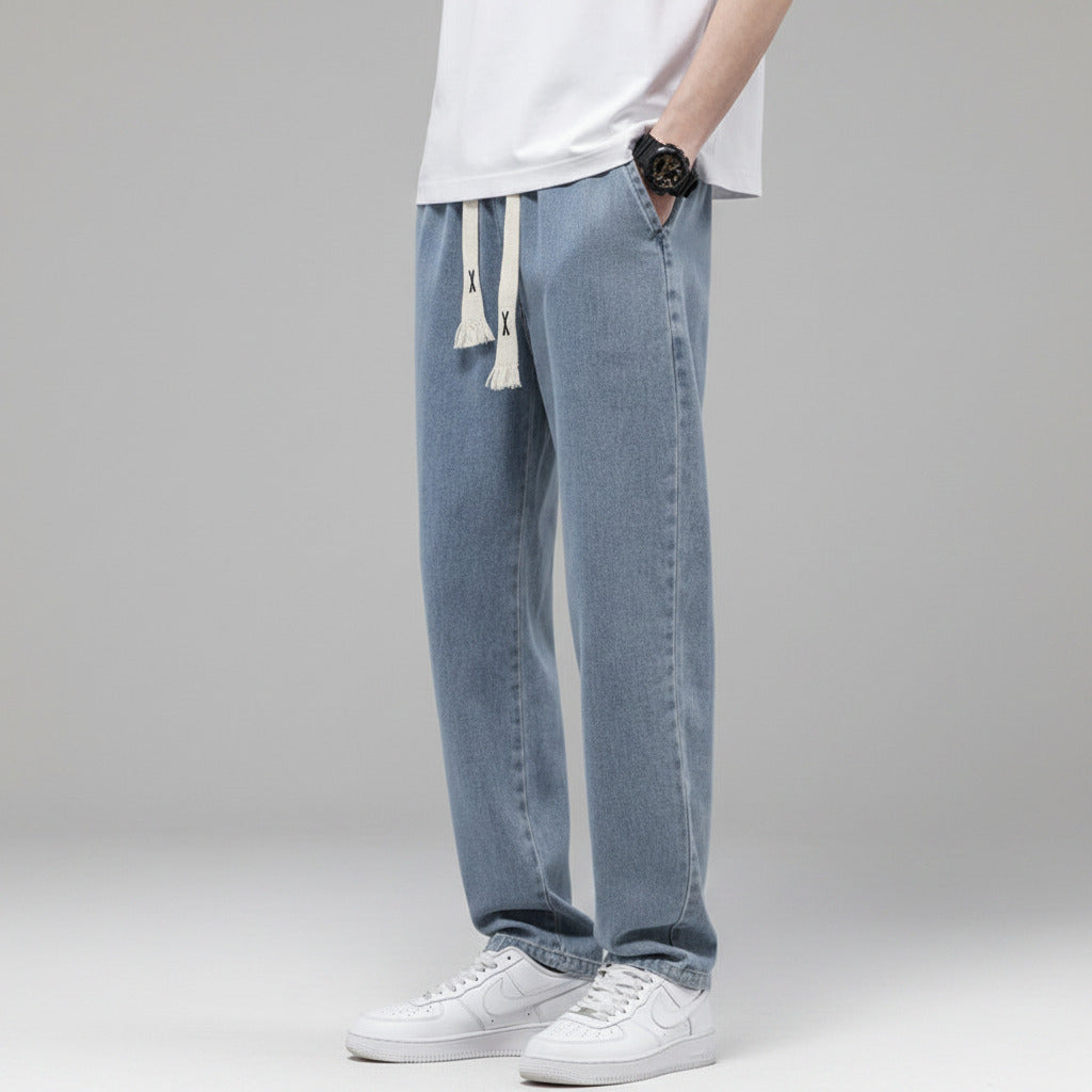 Person wearing light blue jeans and white sneakers against a plain background