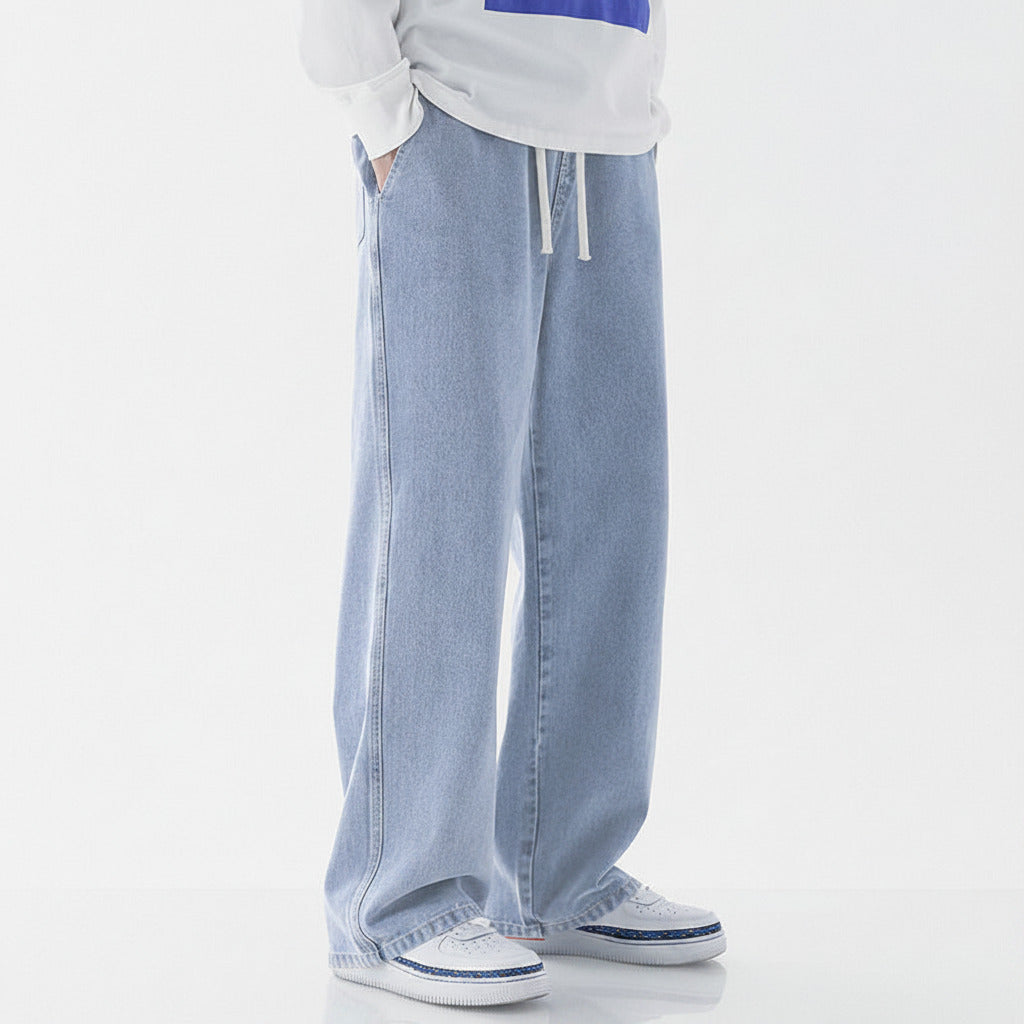 Person wearing light blue jeans and white sneakers on a white background