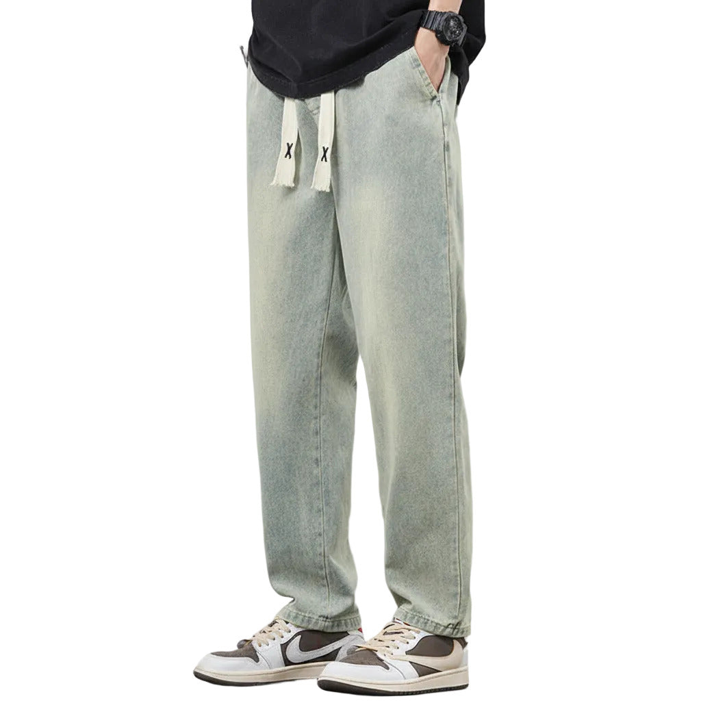 Person wearing light green jeans with a subtle gradient effect on a plain background