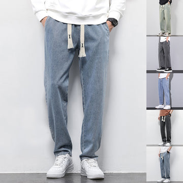 Person wearing light blue jeans with a drawstring, standing against a white wall.