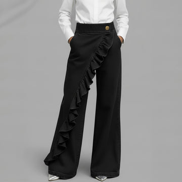 Person wearing wide-leg gray pants with a plain background